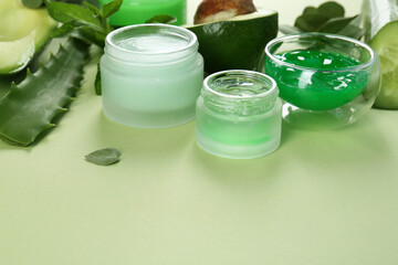 Homemade cosmetic products and fresh ingredients on light green background, closeup. Space for text