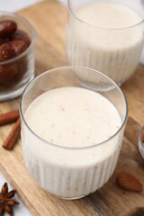 Glasses of delicious date smoothie on wooden board, closeup