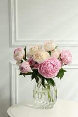 Bouquet of beautiful peonies in glass vase on white table