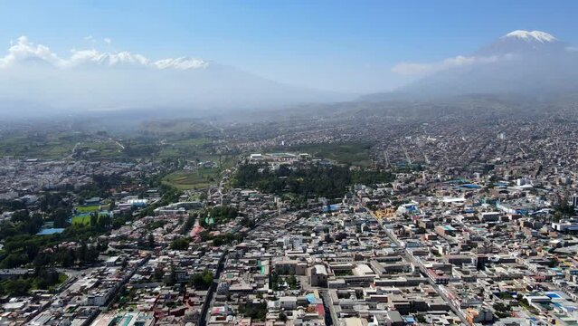 Aerial shot drone flies backwards over Arequipa with Misti Volcano and Chachani Mountains in the distance