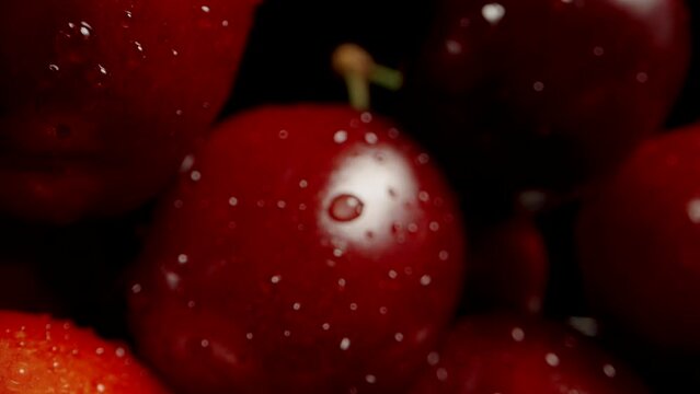 A large abundance of cherries on a table, against a black background. Dolly slider extreme close-up.