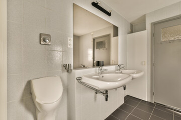 a bathroom with a white toilet and black tile floor in the photo is taken to the right, there is a mirror on the