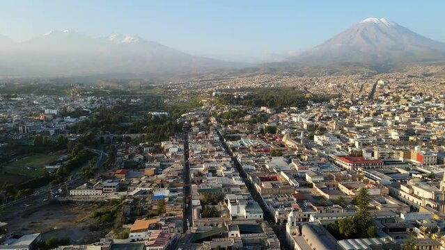 Aerial shot drone flies over Arequipa toward Misti Volcano and Chachani volcano at dusk