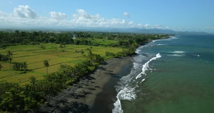 Beautiful beach with black sand and blue water. Drone view of Bali.