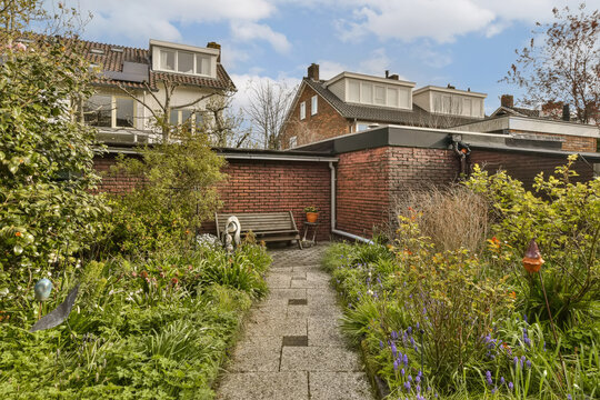 some plants and flowers in front of an old brick house with blue sky background, london, uk stock photo