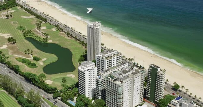 Hang gliding above tall buildings by the beach and ocean, Brazil