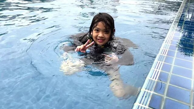 Asian young girl playing in the pool she so happy and joy. She used a plastic bottle of water to save herself from drowning. fitness and relaxation concept