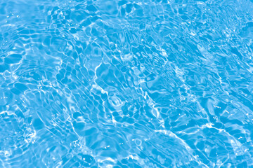 Blue water with ripples on the surface. Defocus blurred transparent blue colored clear calm water surface texture with splashes and bubbles. Water waves with shining pattern texture background.