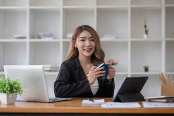 Asian Business woman using calculator and laptop for doing math finance on an office desk, tax, report, accounting, statistics, and analytical research concept