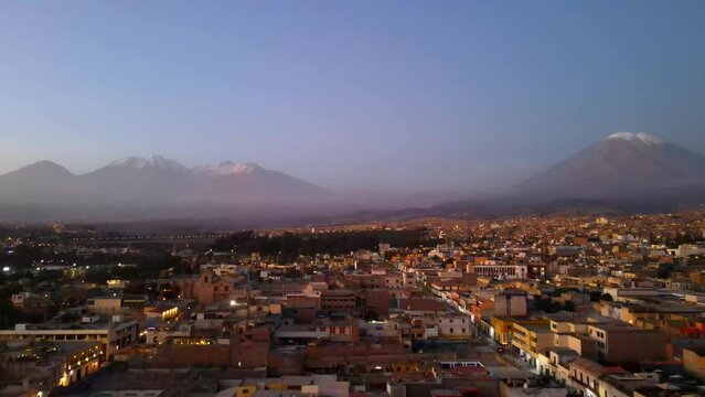 Aerial shot drone flies over Arequipa at sunset toward Misti Volcano and Chachani Volcano
