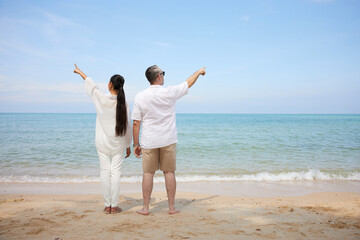 back couple pointing and looking to sky on the sea