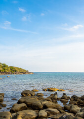 Calm beach scene with blue sea water, ocean and open sky, group of rocks near the coastline beach, seashore scene, coastline, island, summer vacation holiday poster background, vertical style.