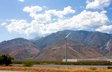 Windmills along the California road near San Bernardino with mountains on the back. Snow on the mountain peak. May 2023