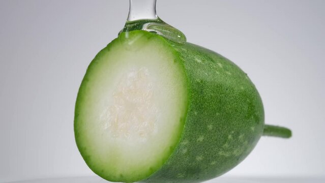 Close up view of a half of winter melon with the transparent essence slowly poured onto it. Cosmetic laboratory research and development
