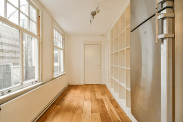 an empty room with wood flooring and white shelvings on the wall in the room is large windows