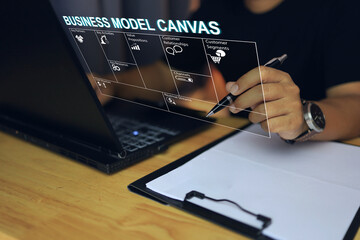 Businessman working with business model canvas through a laptop on the desktop for project presentation and budgeting from high net worth investors value proposition cost and revenue.