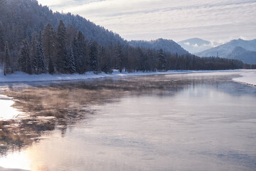 Altai river Biya in winter season. Banks of river are covered by ice and snow.