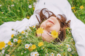 The girl lies in a clearing with wild flowers and herbs and looks into the camera © EdNurg