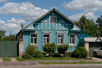 Fototapeta na wymiar Russian traditional wooden house decorated with house carvings and a front garden on a sunny summer day, Suzdal, Vladimir region, Russia