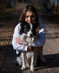 Caucasian woman hugging border collie in autumn park. Portrait of a girl with a dog.