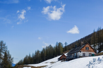 alpine hut on a snowy mountain with blue sky and little clouds