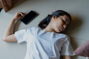 Asian woman fainting at home with The phone fell close to his hand.