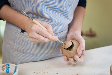 woman forming clay pot shape by hands, closeup in artistic studio