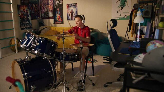 Young boy plays on drum kit at home. Elderly man irritated by noisy neighbor, screams, knocks on wall. Low level of sound insulation. Apartments separated by wall. Neighbourhood concept. Dolly shot.