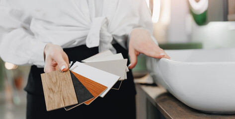 Beautiful Woman seller advising female client with tiles color samples, sinks and texture of cabinets for bathroom banner