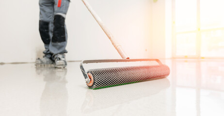 Master with needle roller for new screed concrete with mixture of cement for leveling for floors...
