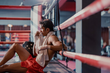 Fototapeta na wymiar Professional boxer feels exhausted, fatigued after putting up intense effort and discipline while following a training schedule. Strict diets that help with physical fitness also lead to burnout.