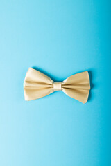 Overhead view of white bowtie isolated against blue background, copy space
