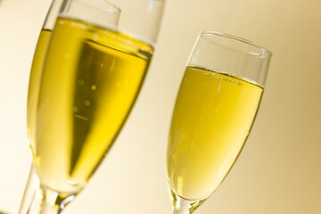 Close-up of champagne in champagne flutes against beige background, copy space
