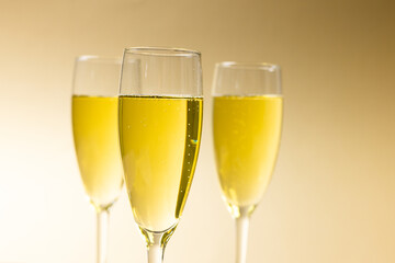 Close-up of champagne flutes with champagne against beige background, copy space