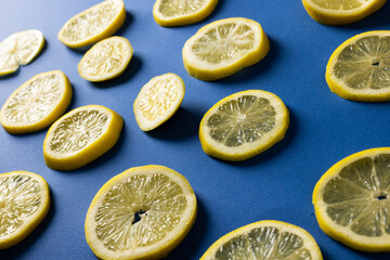 High angle view of lemon slices arranged against blue background, copy space