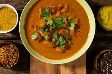 Directly above shot of meat gravy garnished with cilantro and spices with lentils in bowls on table