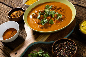 High angle view of meat gravy in bowl with spices, cilantro and lentils over wooden table
