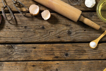 High angle view of eggshells with rolling pin, whisks and sugar in wooden spoon on table