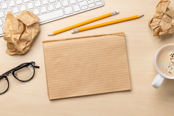 Top view of blank notepad, keyboard, coffee, apple and crumpled papers