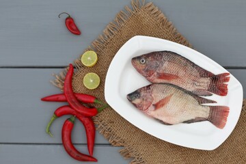 Tilapia, fresh fish on a wooden table, gray background