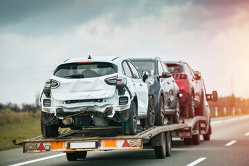 Tow truck with broken car on country road. Tow truck transporting car on the highway. Car service transportation concept.