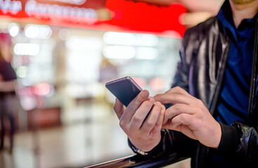 A man writes in her smartphone at the mall
