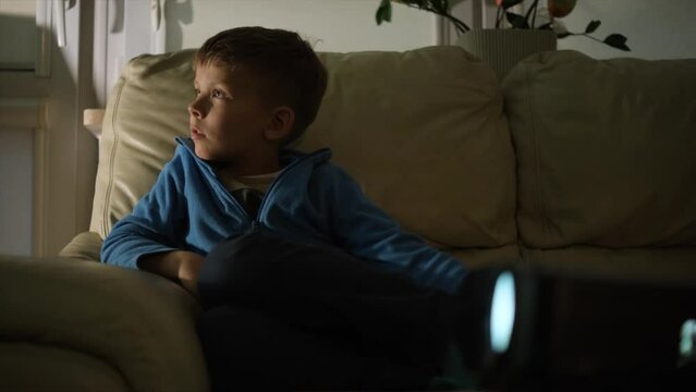 A boy watches a movie on a projector. Home theater.
