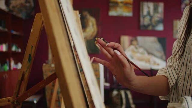 Embracing the Unknown: In her studio, a female painter fearlessly explores modern abstract art. With a brush and oil paints, she transforms the canvas, birthing dark masterpieces