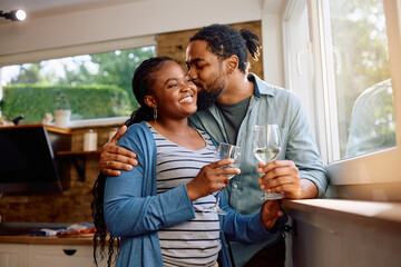 Happy black couple enjoys in their love and glass of wine at home.