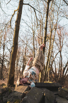 dancer balances in strong hold on stones in winter forrest