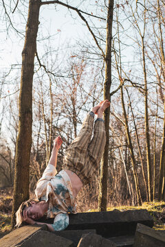 strong athletic dancer balances gracefully on one shoulder in forrest