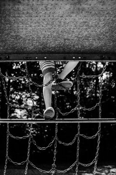 Faceless image of child climbing on playground equipment at park