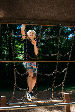 Child climbing on metal playground epuipment at park during summ