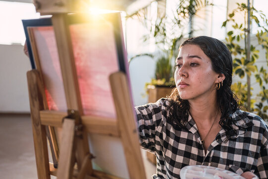 Artist woman painting on canvas at sunset.  Natural light